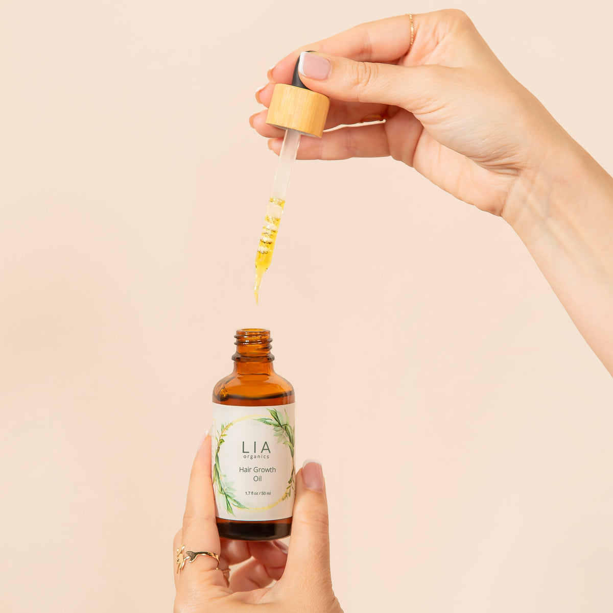 Original product photograph: hands holding the 50 ml Hair Growth Oil bottle and glass dropper.