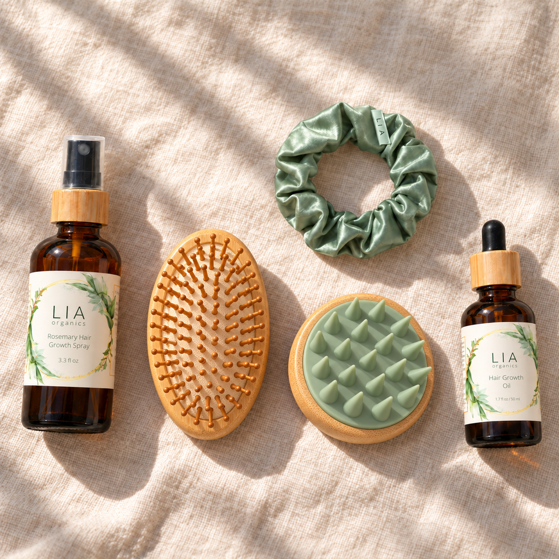 LIA Organics Ultimate Gifting Kit: Rosemary Tonic 3.3 fl oz, Hair Growth Oil 50 ml, bamboo brush with bristles visible, bamboo scalp massager with green tips visible, and silk scrunchie.