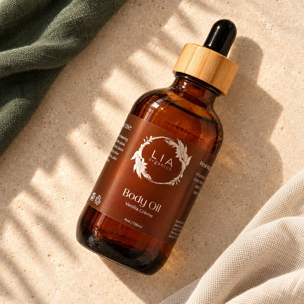 Full-size Lia Organics Body Oil bottle lying on cream stone and linen